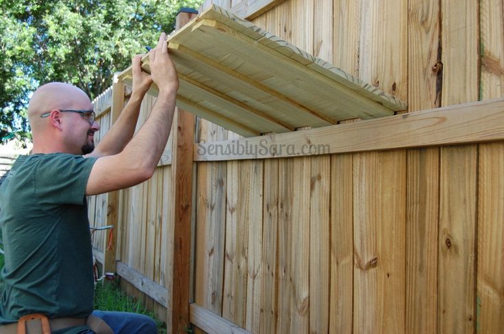 a man working on a wooden fence