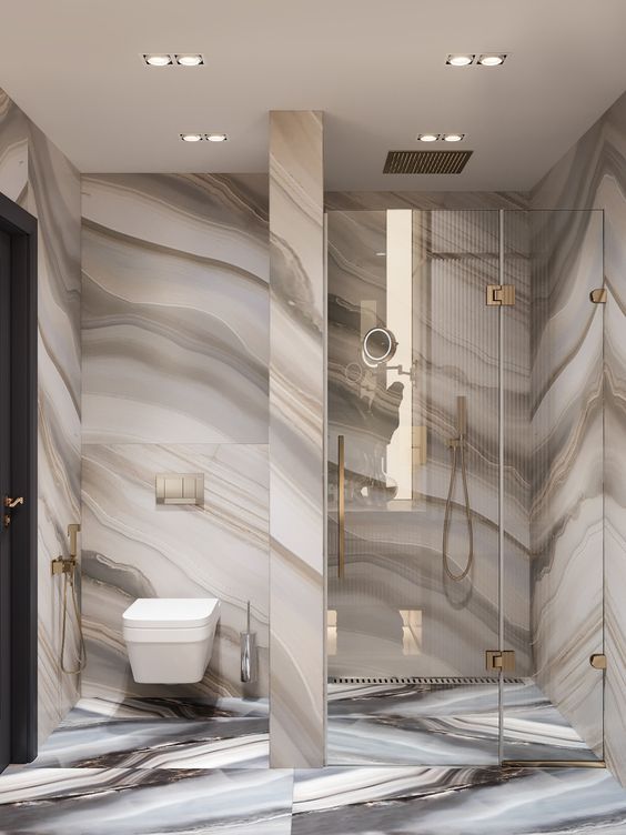 a bathroom with marbled walls and flooring, including a glass enclosed shower stall