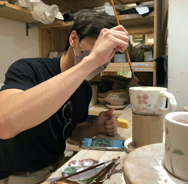 a man sitting at a table working on something with a wooden stick in his hand