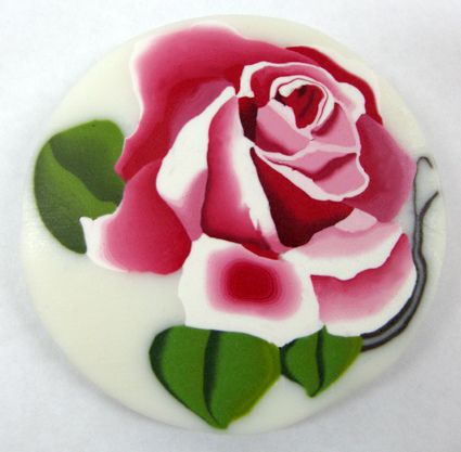 a pink and white rose is on top of a round cake that has green leaves