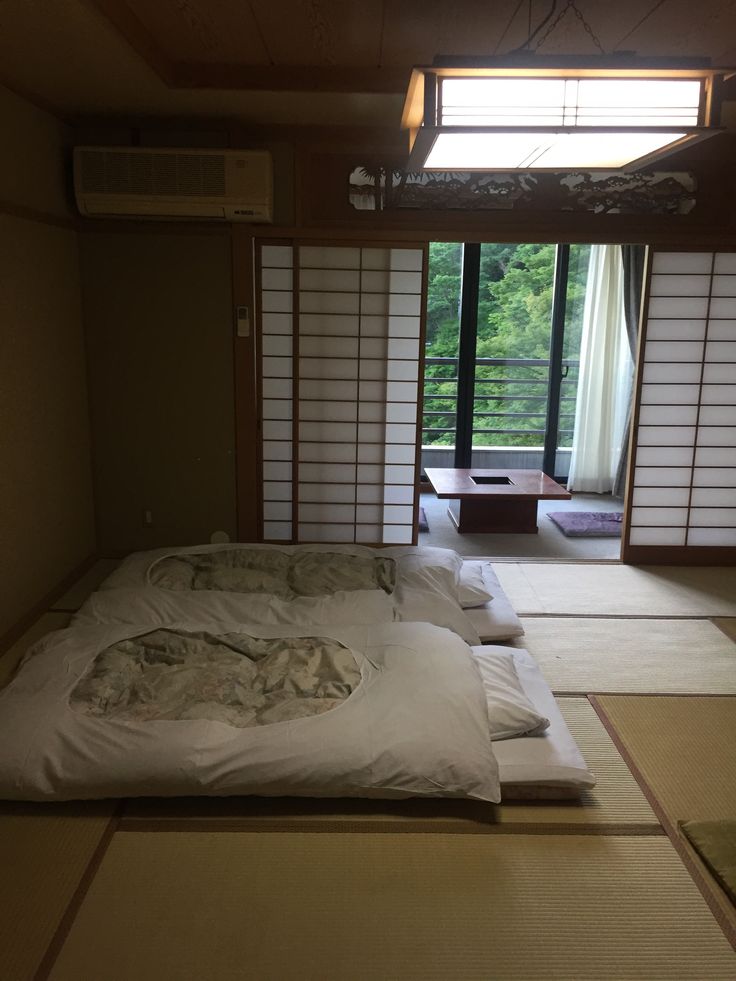 there is a bed with white sheets and pillows on it in the room that has sliding glass doors