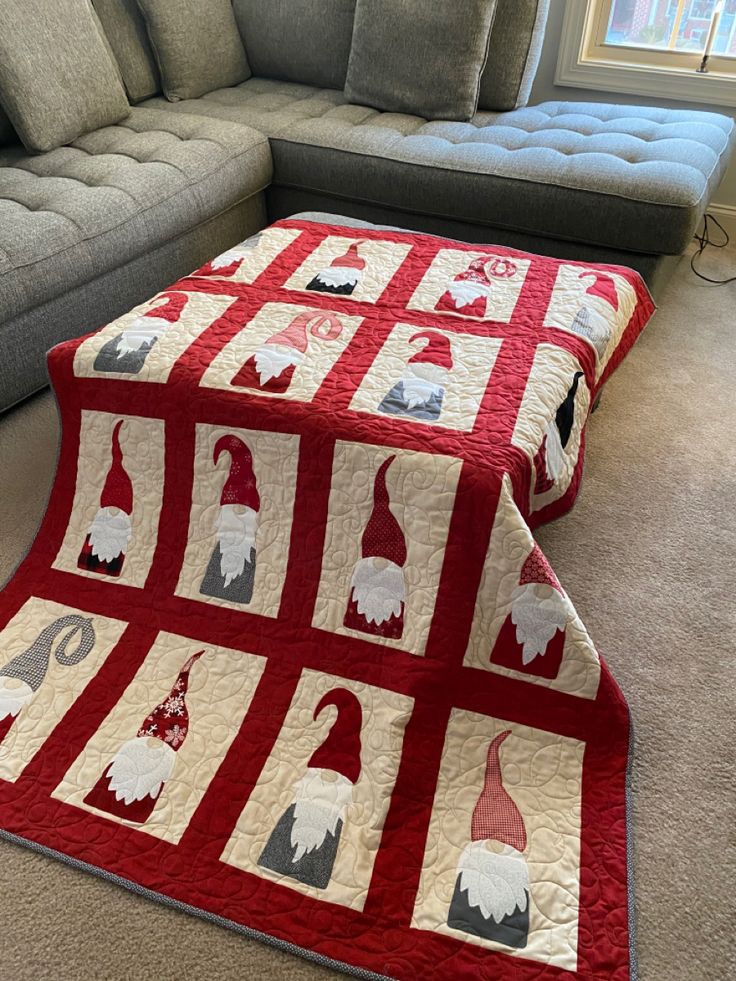 a living room with a couch and a quilted table runner on the floor in front of it