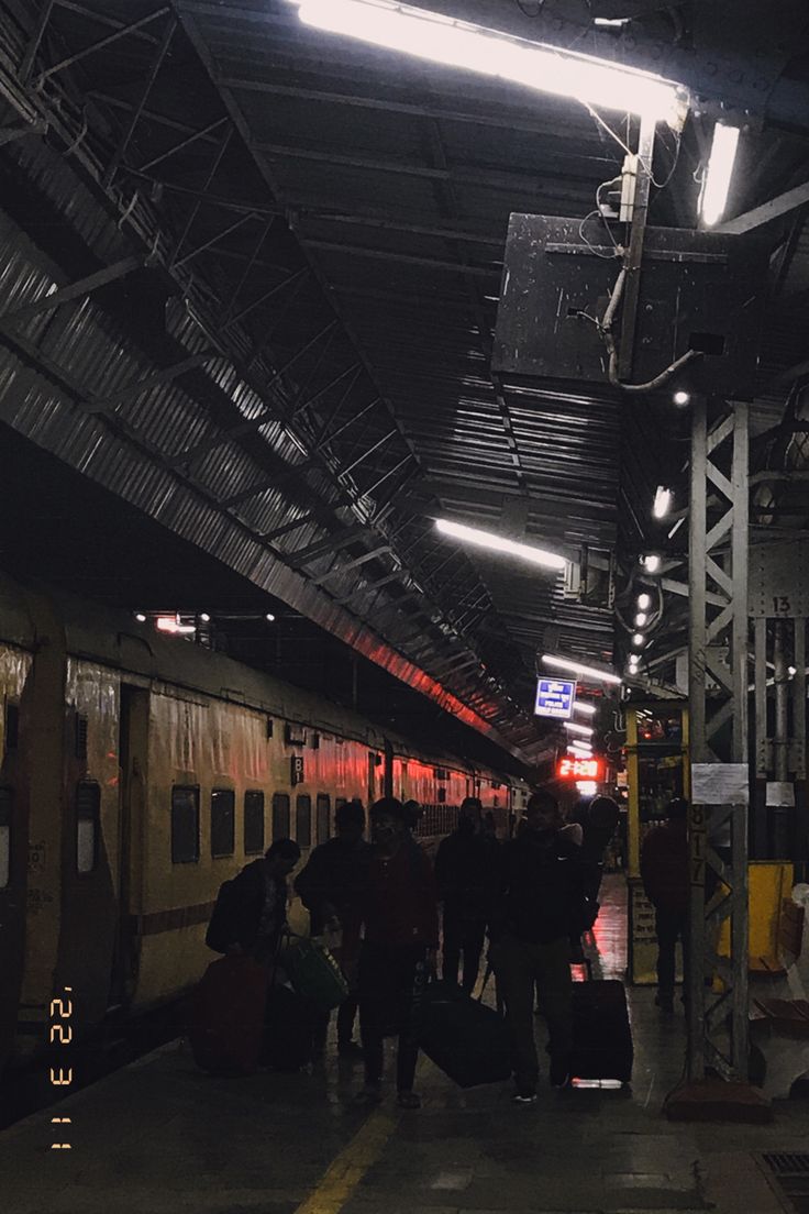 several people are standing on the platform with their luggage in hand and waiting for the train to arrive