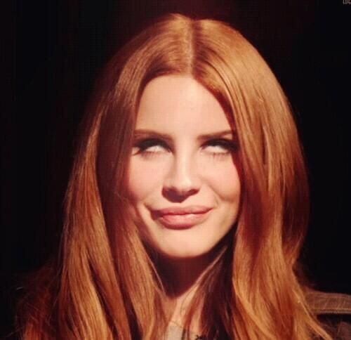 a woman with long red hair smiling at the camera