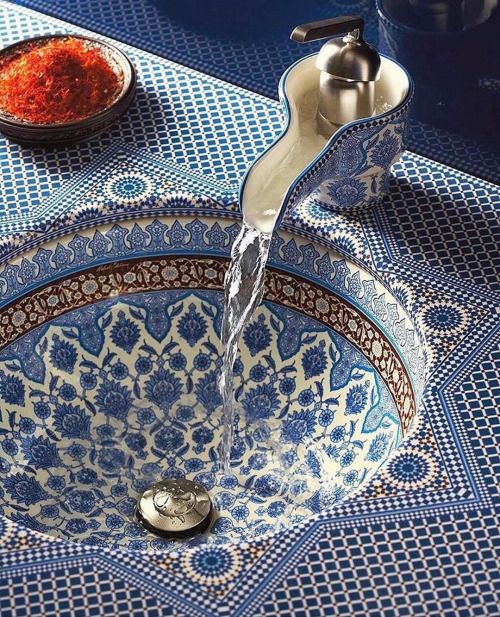 a faucet that is sitting on top of a blue and white bowl with red stuff in it