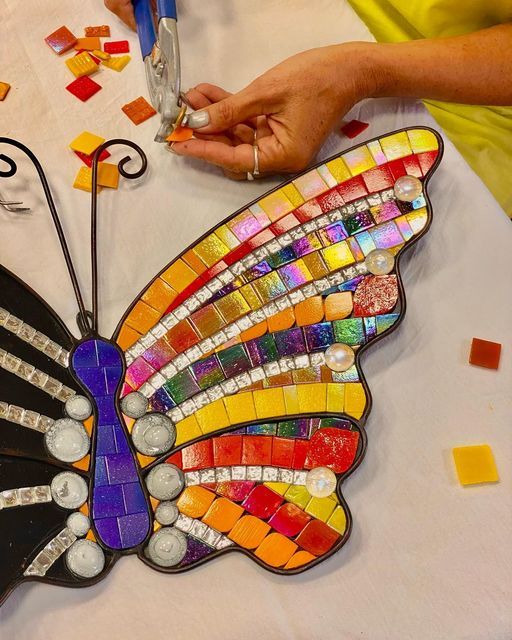 a colorful butterfly made out of glass sitting on top of a table next to scissors