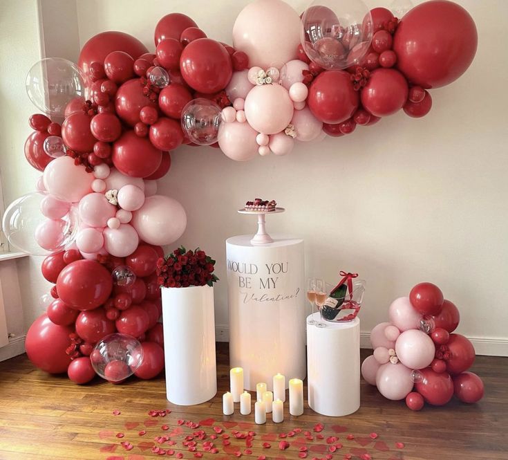 balloons and candles are arranged on the floor in front of a large arch made out of balloons