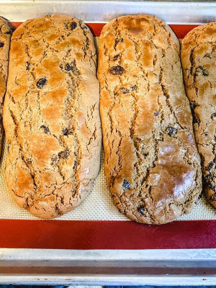 four loaves of bread sitting on top of a red and white baking pan,