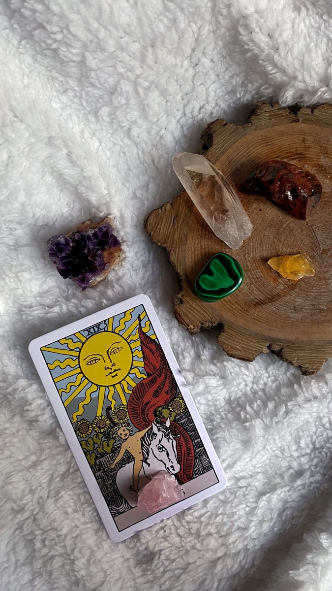 the tarot card is next to some other items on a white blanket with a wooden plate