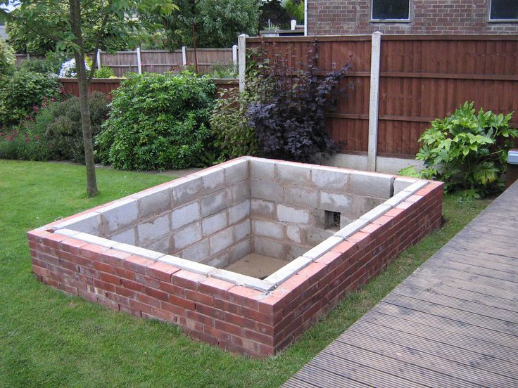 a brick fire pit sitting in the middle of a yard