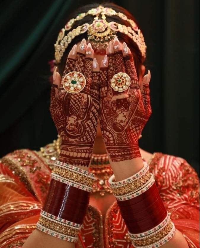 a woman with her hands covered in hendi and jewelry, showing the intricate designs on her hands