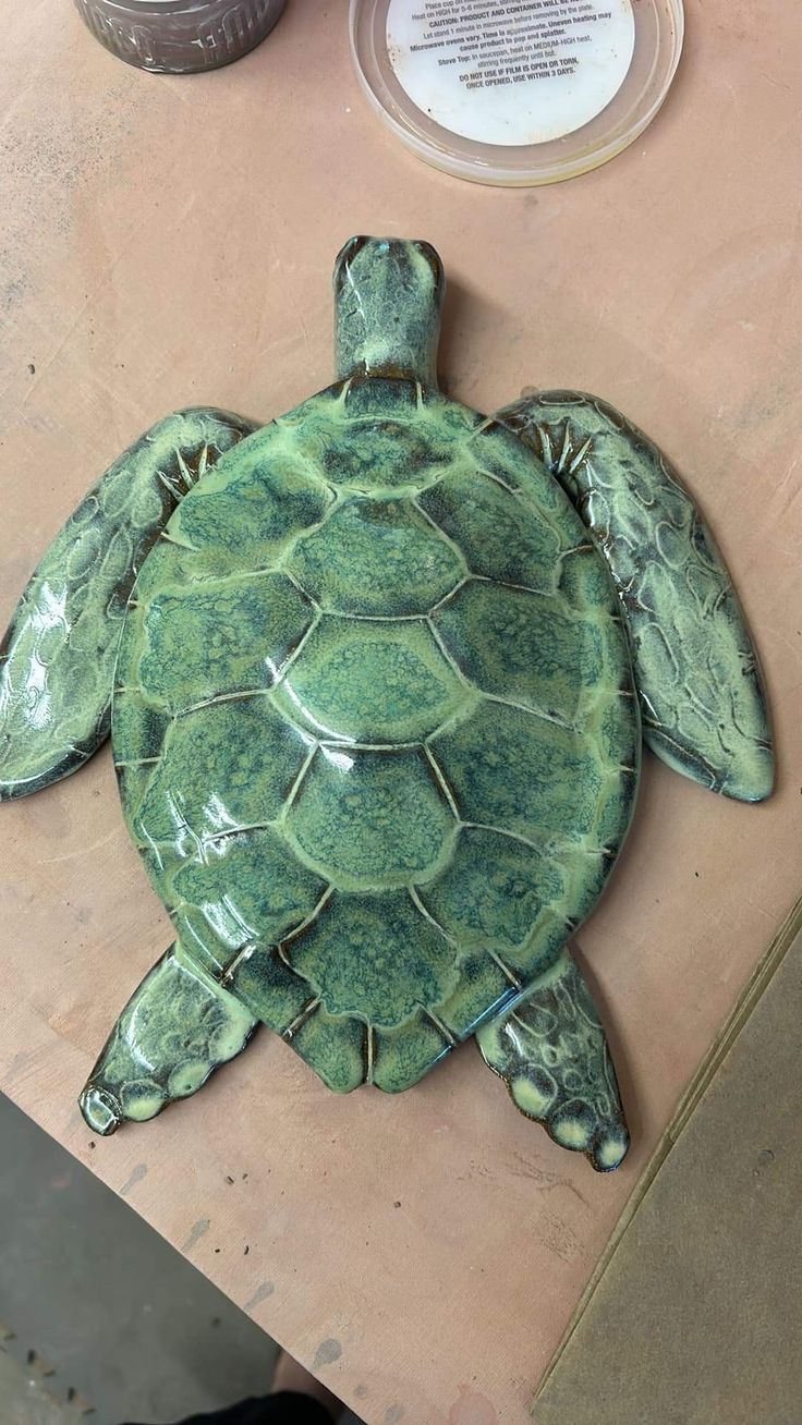 a green turtle statue sitting on top of a wooden table