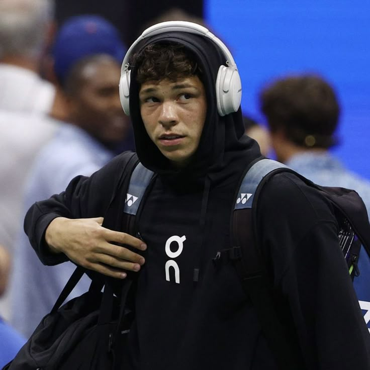 a young man wearing headphones walking in front of a crowd