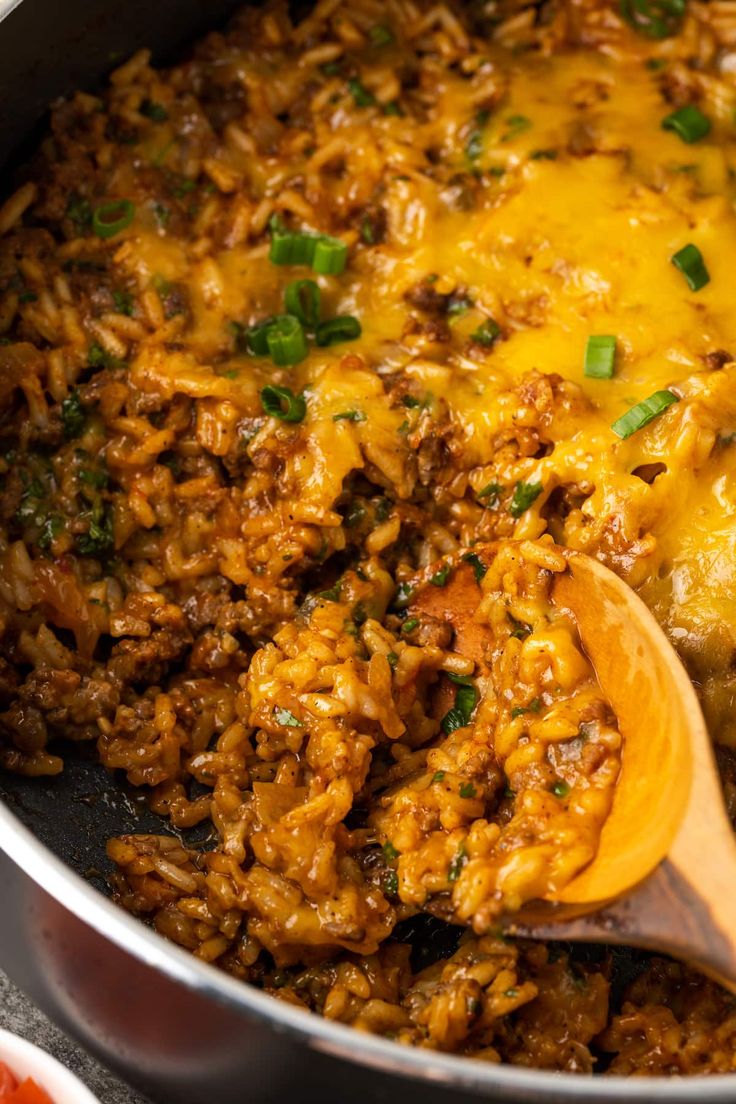 a skillet filled with rice and meat covered in cheese