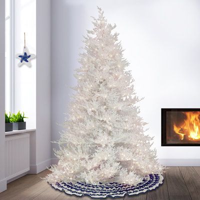 a white christmas tree in front of a fireplace