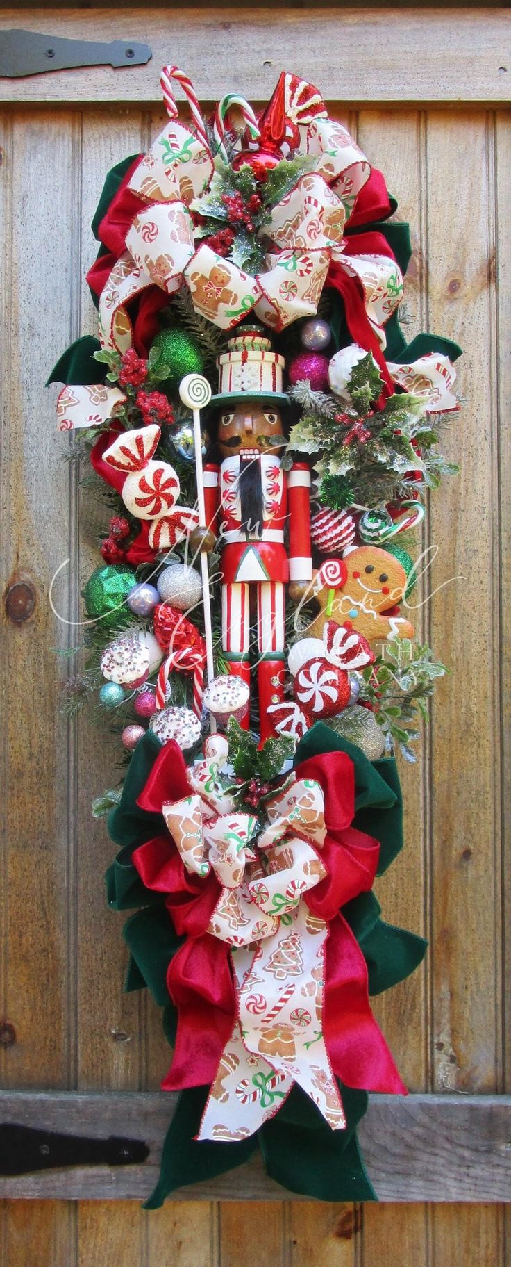 a christmas wreath with candy canes, candies and other holiday decorations hanging on a wooden door