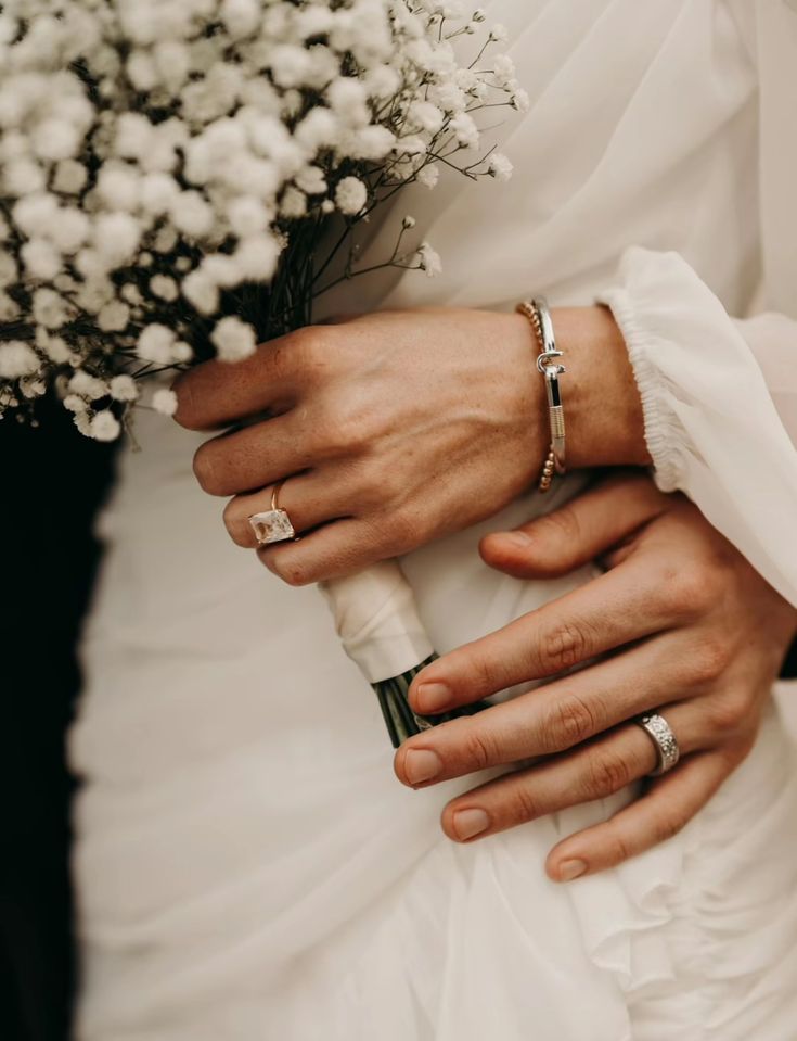 the bride and groom are holding each other's hands with wedding rings on their fingers