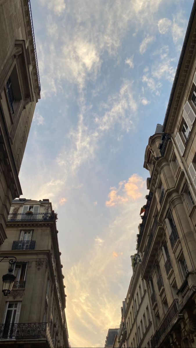 looking up at the sky from an alley way in paris, france with tall buildings