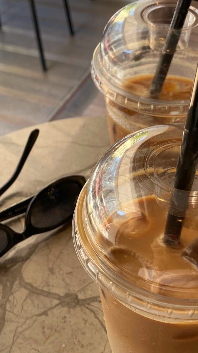 two iced coffees sitting next to each other on a table