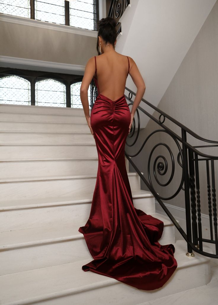 Our Love Affair Satin gown in Wine features a silky satin fabric, ruched back design and a deep V neckline to give you the perfect contoured shape. With its luxurious satin material, the Love Affair ball gown is the perfect figure-hugging maxi dress for prom season. The satin gown drapes perfectly into a fishtail design on the lower half of the maxi dress which is key for those picture-perfect prom pictures. Pair with gold jewellery and a matching gold bag to win best dressed at your black-tie a Red Silk Prom Dress, Wine Red Prom Dress, Red Backless Dress, Red Prom Dress Long, Wine Red Dress, Silk Prom Dress, Dress For Prom, Red Satin Dress, Prom Season