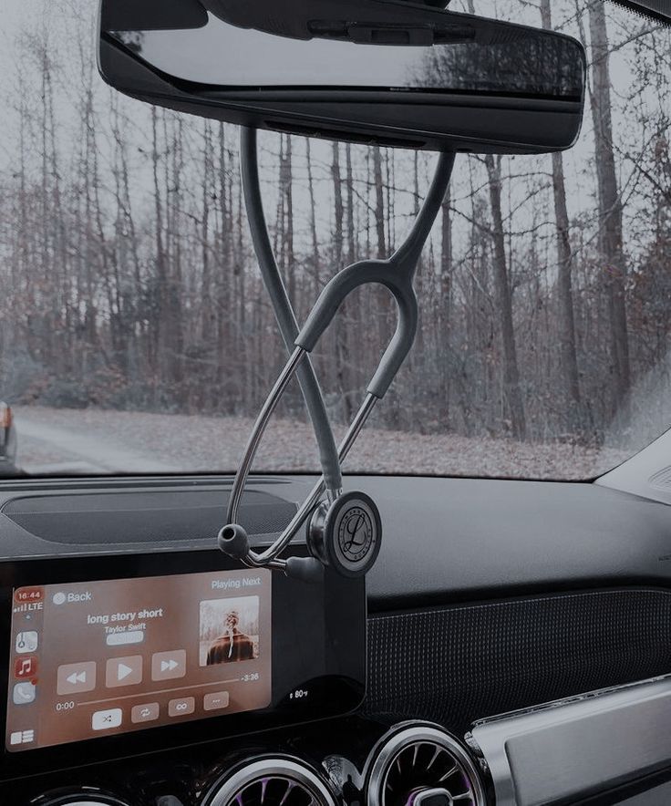 an electronic device is attached to the dashboard of a car with trees in the background