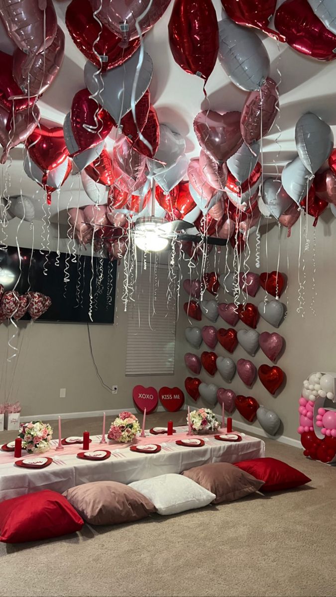 a room filled with lots of red and white heart shaped balloons hanging from the ceiling