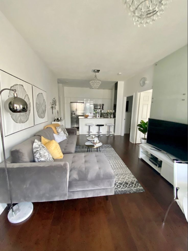 a living room filled with furniture and a flat screen tv on top of a hard wood floor