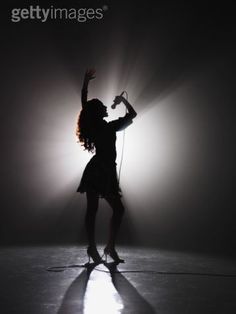 a woman is dancing in the dark with her arms up and headphones hanging down