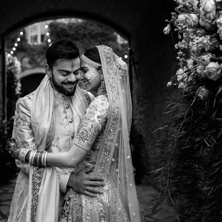 the bride and groom are embracing in front of an arch with flowers on it at their wedding