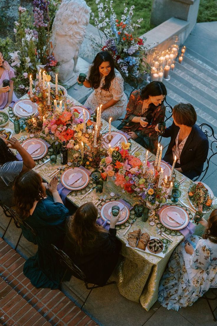 a group of people sitting around a table with plates and candles in front of them