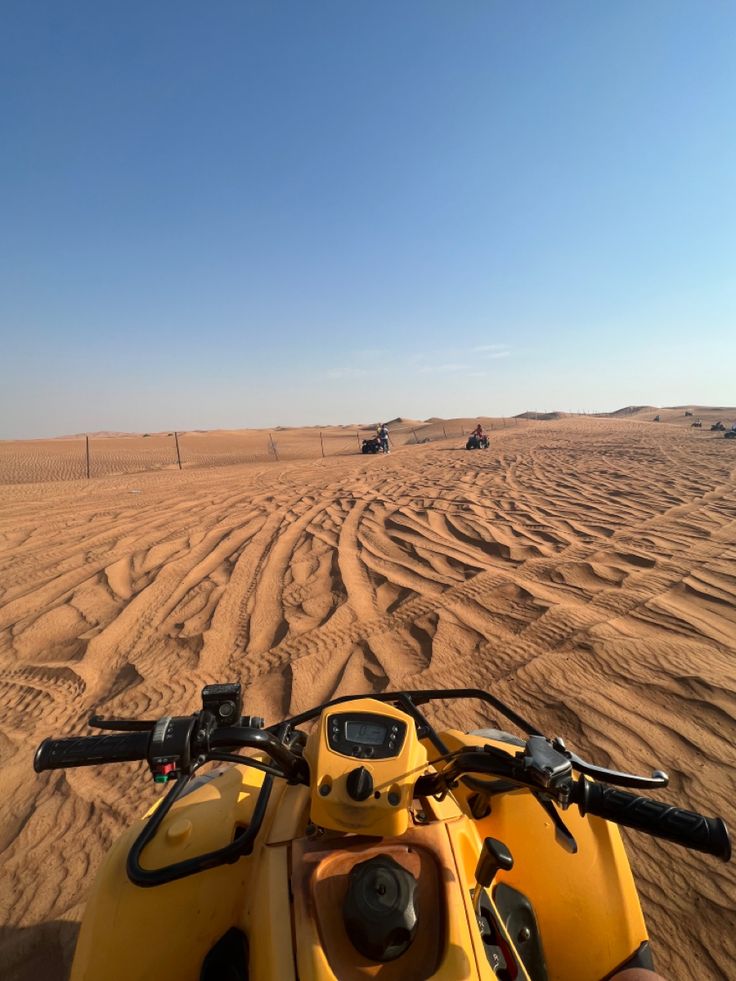 two atvs driving in the desert on a sunny day with no people or vehicles