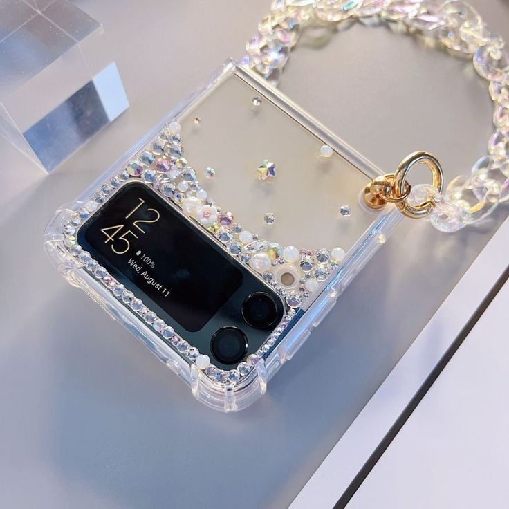 a cell phone with a chain attached to it sitting on top of a table next to a box