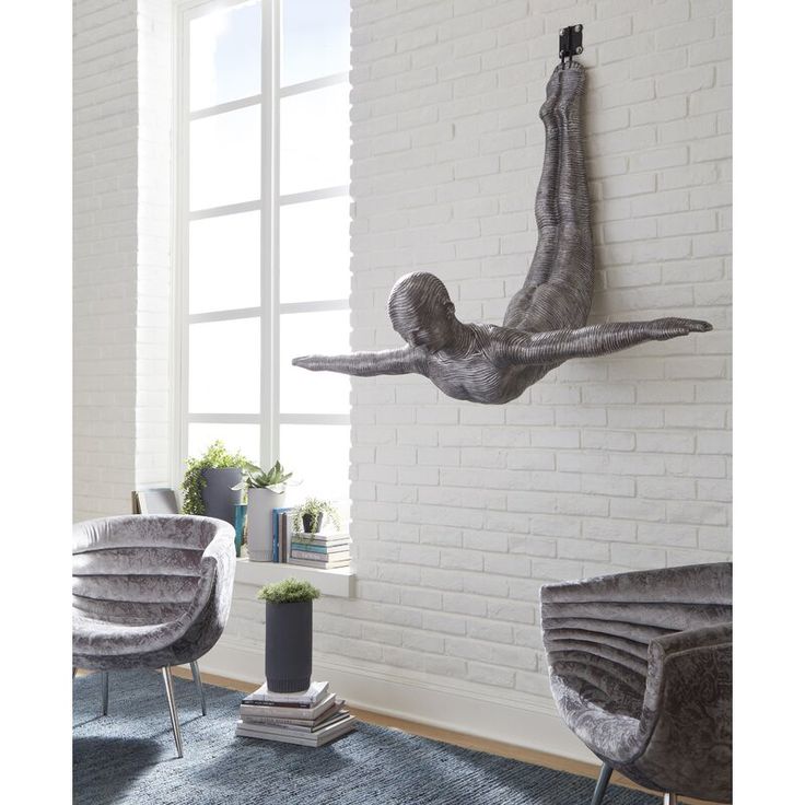 a sculpture of a person falling off the side of a building in front of a window