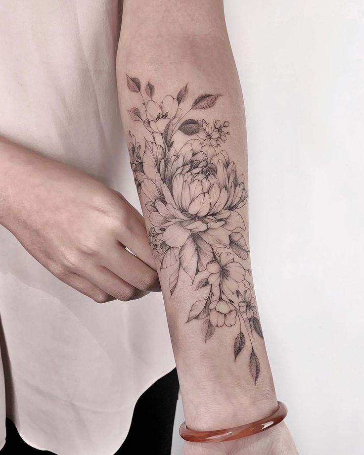 a woman's arm with a flower tattoo on the left side of her arm