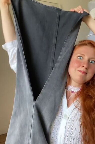 a woman with red hair is holding up a piece of cloth