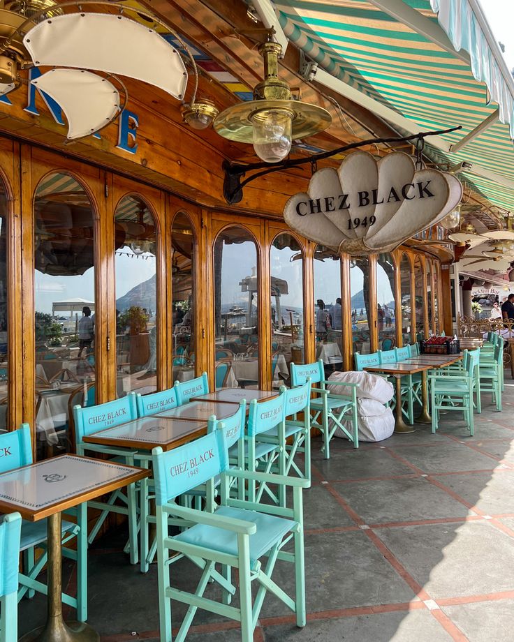 tables and chairs are lined up on the outside of an outdoor restaurant with large windows