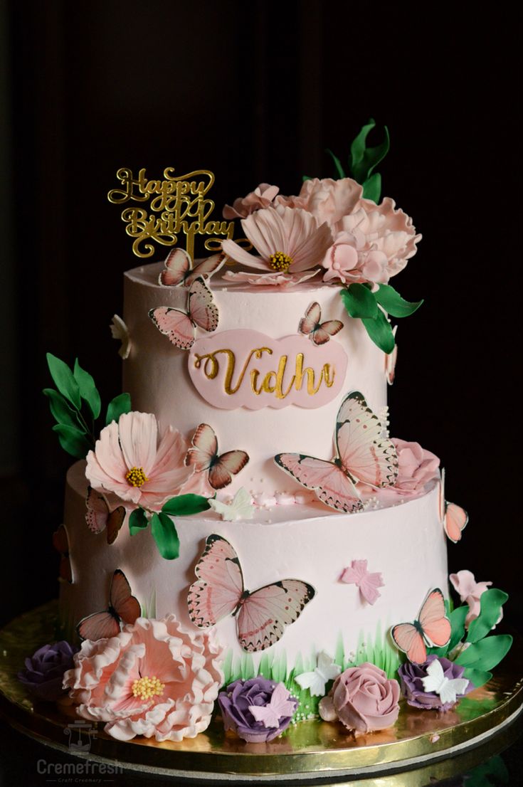 a three tiered cake decorated with pink flowers and butterflies