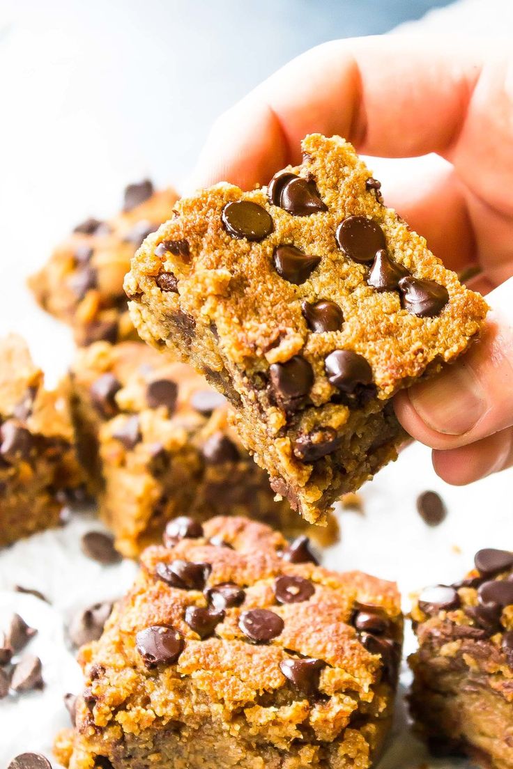 someone holding up a cookie bar with chocolate chips