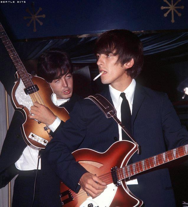 two young men in suits are playing guitars