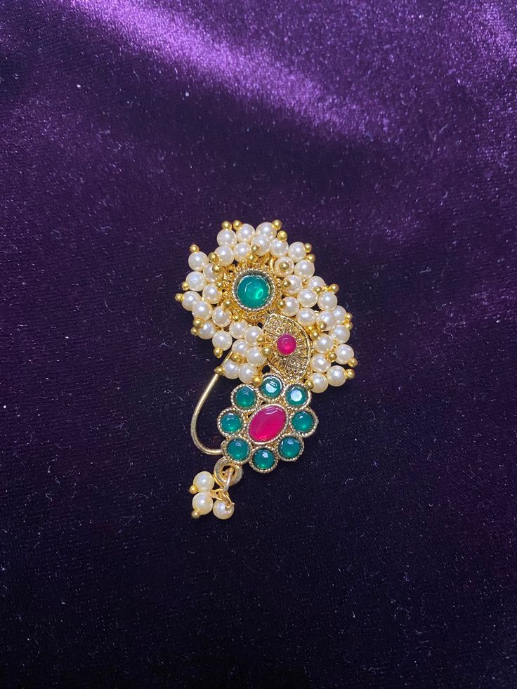 Add a touch of traditional elegance to your look with our Maharashtrian Nose Pin. This Indian Nath is a perfect accessory for lavani dance costumes, Marathi wedding bridesmaids, or anyone looking to embrace Indian culture. Nose Pin Length: 4.00 CM Metal: Alloy With Good Quality Gold Plated Color: Maroon & Green Stone: Glass Stone Faux pearls Put small-piece of double tape on nose and press the nath on it to secure it. Jewellery Care- Keep the jewellery dry, avoid contact with perfumes and water. Lavani Dance, Maharashtrian Nath, Nose Pin Indian, Marathi Nath, Nath Nose Ring, Bridal Nose Ring, Marathi Wedding, Aadi Shakti, Beautiful Bridal Jewelry