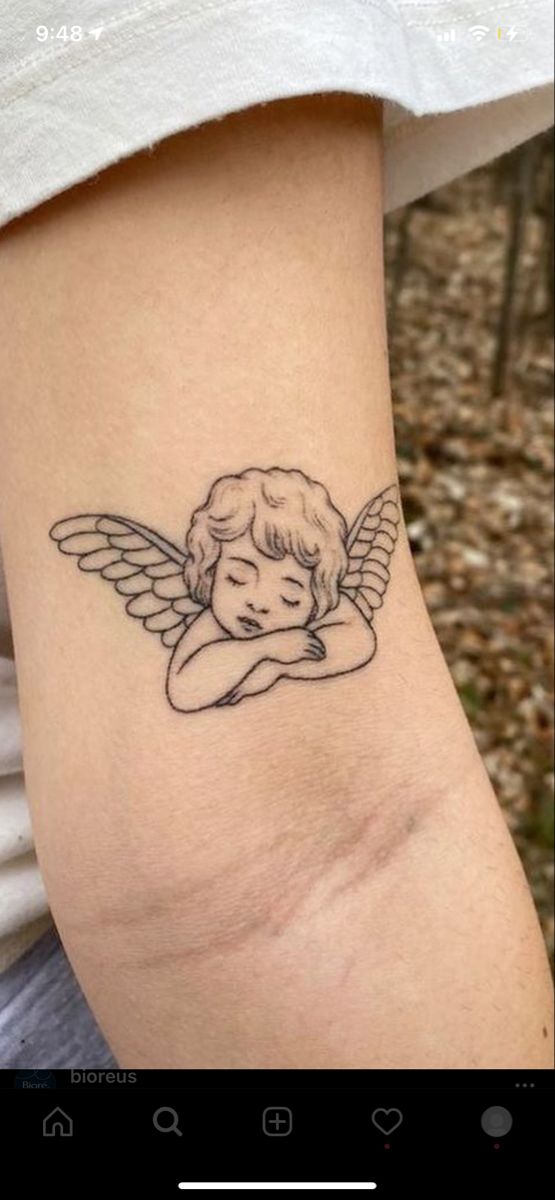 a small tattoo on the arm of a woman with an angel wings and a heart