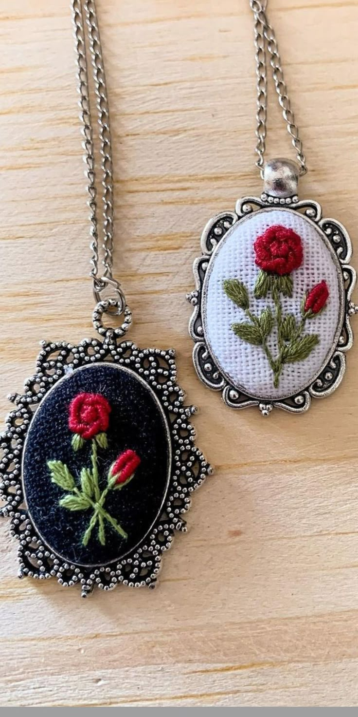 two pendants with flowers on them sitting on a wooden table next to each other