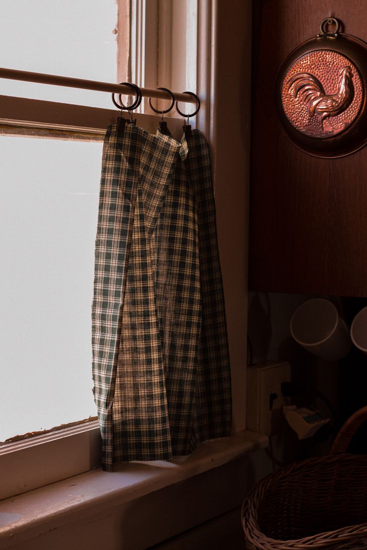 a window sill with a curtain hanging from it's side next to a basket