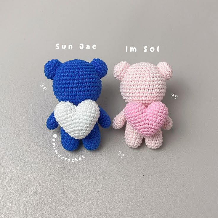 two small crocheted teddy bears sitting next to each other on a gray surface