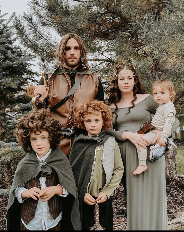 a group of people standing next to each other in front of some trees and pine trees