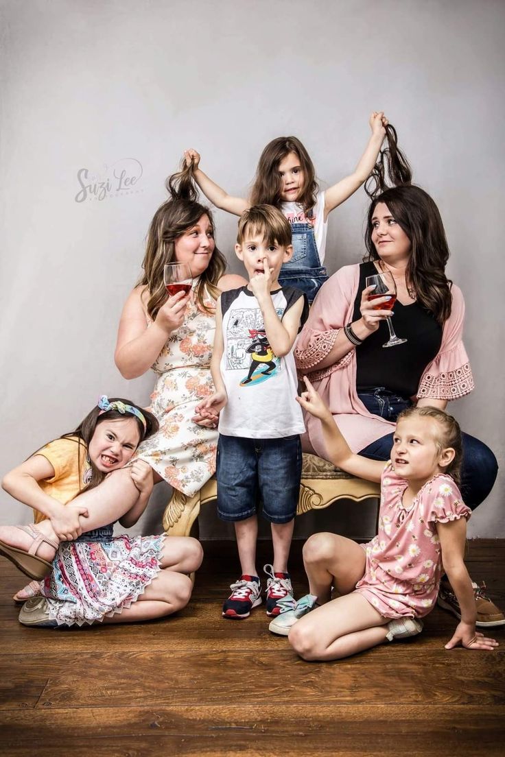 a group of people sitting on top of a wooden floor with wine glasses in their hands