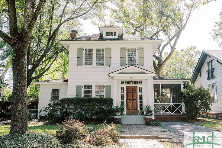 a white house with trees and bushes around it