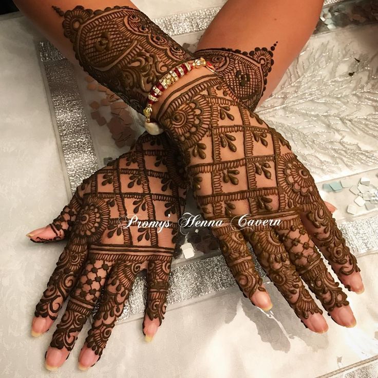 two hands with henna tattoos on them, one is showing the intricate pattern and the other