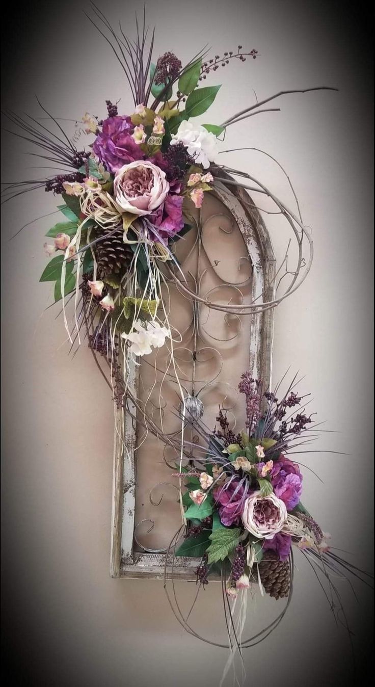 an old window is decorated with purple flowers and greenery as well as dried pine cones