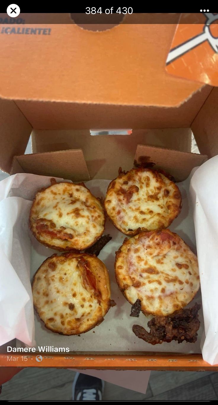 four mini pizzas sitting in a box on top of a table